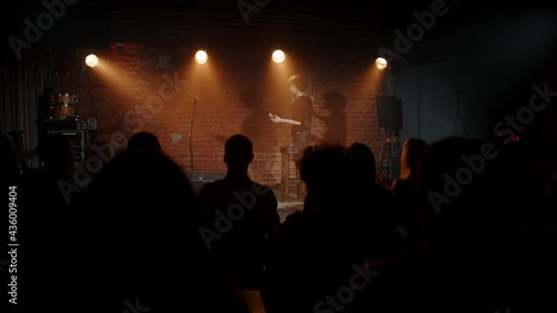 DOLLY Young Caucasian male comedian entering stage and greeting audience, performing his stand-up monologue inside a small venue. Shot with ARRI Alexa Mini LF with 2x anamorphic lens photo