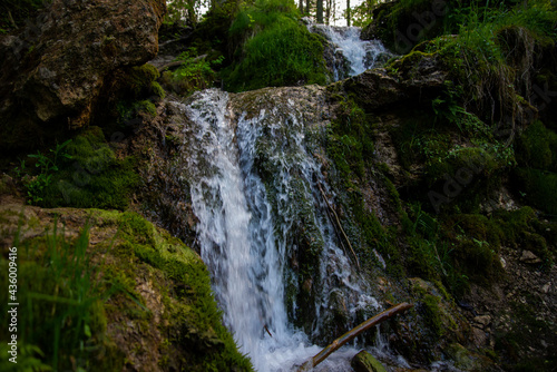 Beautiful mountain rainforest waterfall with fast flowing water and rocks, long exposure. Natural seasonal travel outdoor background with sun shihing photo