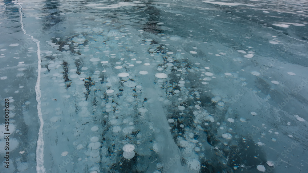 Ice surface. Close-up. Full screen. Cracks and columns of frozen methane gas bubbles are visible. Lake Baikal in winter.