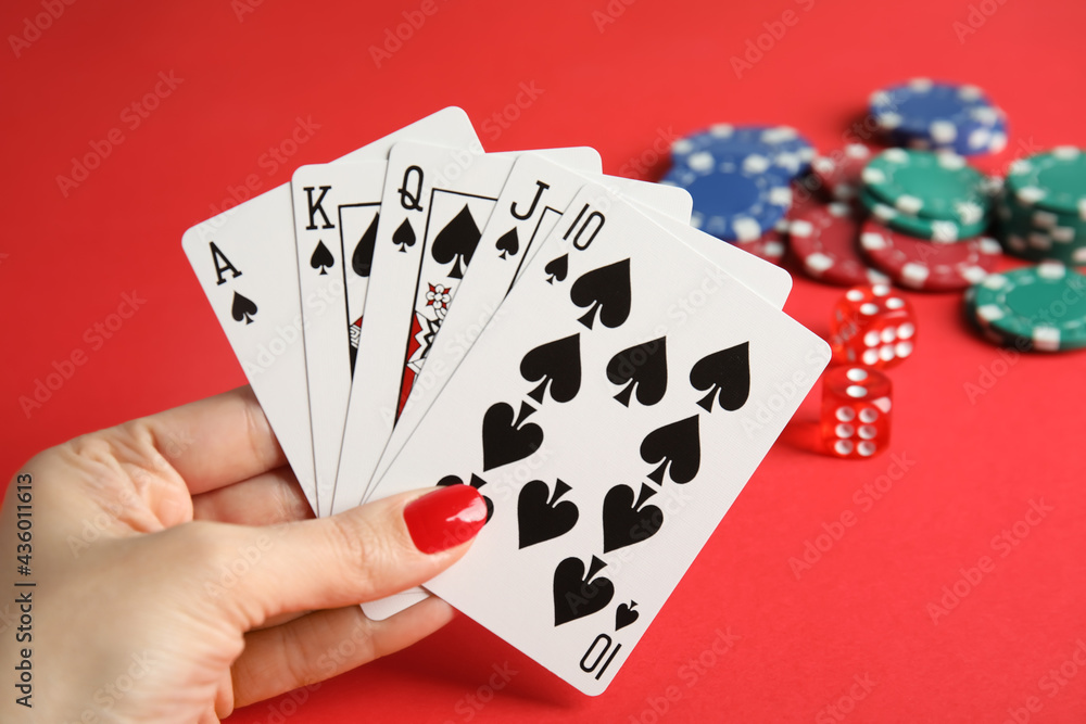 Woman holding playing cards with royal flush combination at red table, closeup Woman holding playing cards with royal flush combination at red table, closeup