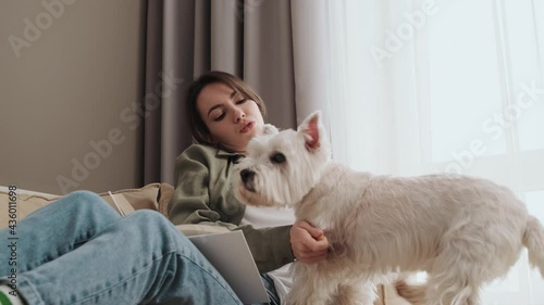 Wallpaper Mural A cheerful girl is petting her dog while reading a book sitting at home Torontodigital.ca