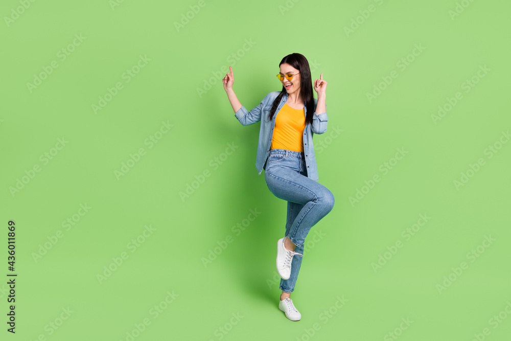 Full size photo of young stunning charming smiling woman in sunglass dancing having fun isolated on green color background