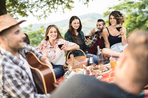 Group of people having fun eating and drinking wine at picnic party outdoor - Main focus on front girl faces