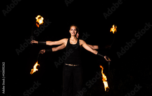 Happy couple of fire performers spin burning pois at night dark outdoors, action photo