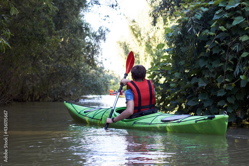 Man paddle green kayak on summer Danube river. Summer kayaking. Concept for adventure, travel, action, lifestyle