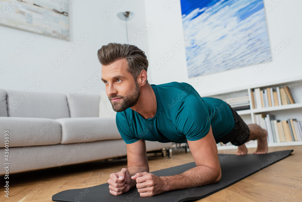 Fototapeta premium barefoot man practicing yoga in plank pose at home