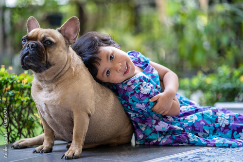 Fototapeta Naklejka Na Ścianę i Meble -  Cute little girl sitting with French bulldog at garden.