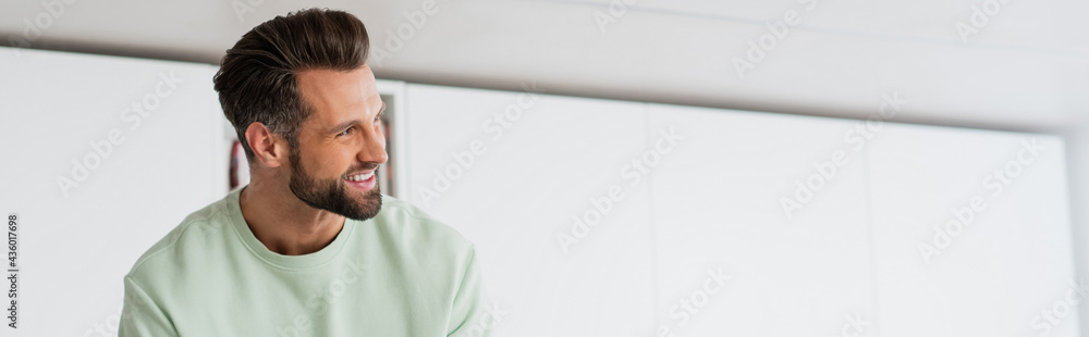 adult man smiling while looking away at home, banner - obrazy, fototapety, plakaty 