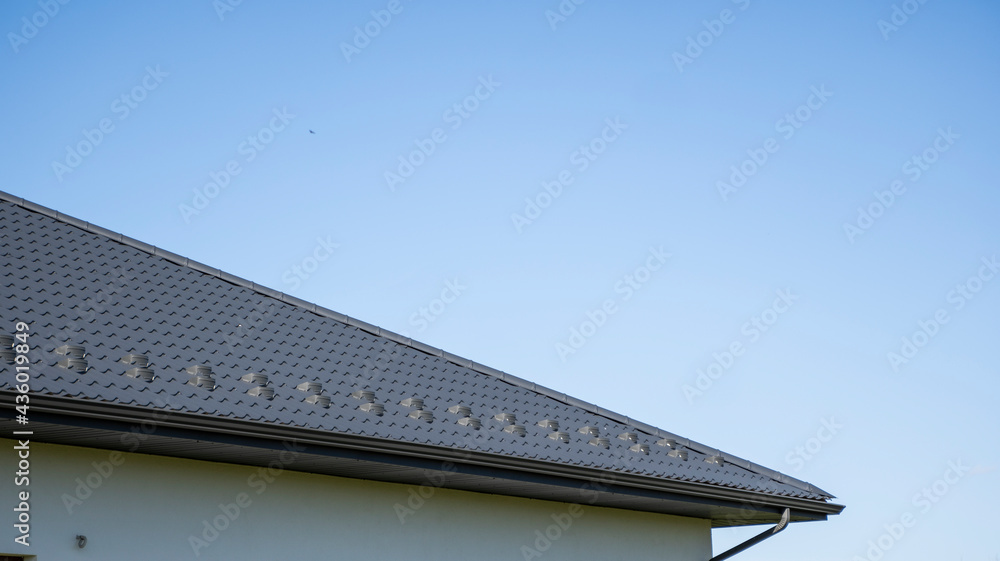 Grey corrugated metal profile roof installed on a modern house. The roof of corrugated sheet. Roofing of metal profile wavy shape. Modern roof made of metal. Metal roofing. Grey corrugated metal profile roof installed on a modern house. The roof of corrugated sheet. Roofing of metal profile wavy shape. Modern roof made of metal. Metal roofing.