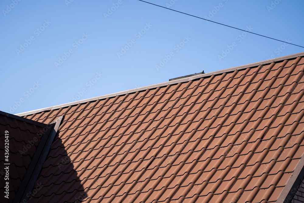 Brown corrugated metal profile roof installed on a modern house. The roof of corrugated sheet. Roofing of metal profile wavy shape. Modern roof made of metal. Metal roofing. Brown corrugated metal profile roof installed on a modern house. The roof of corrugated sheet. Roofing of metal profile wavy shape. Modern roof made of metal. Metal roofing.