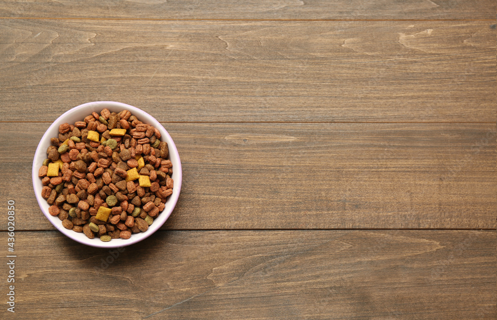Dry food in pet bowl on wooden background, top view. Space for text Dry food in pet bowl on wooden background, top view. Space for text