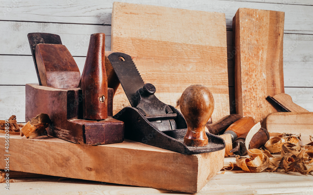 Photo of wooden old fashioned planes with carving chisels laying on workbench table. Photo of wooden old fashioned planes with carving chisels laying on workbench table.