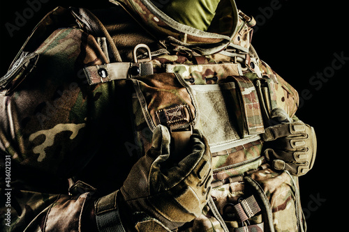 Tableau sur toile Photo of soldier in level 3 armored vest ammunition, tactical gloves using pouch on black background