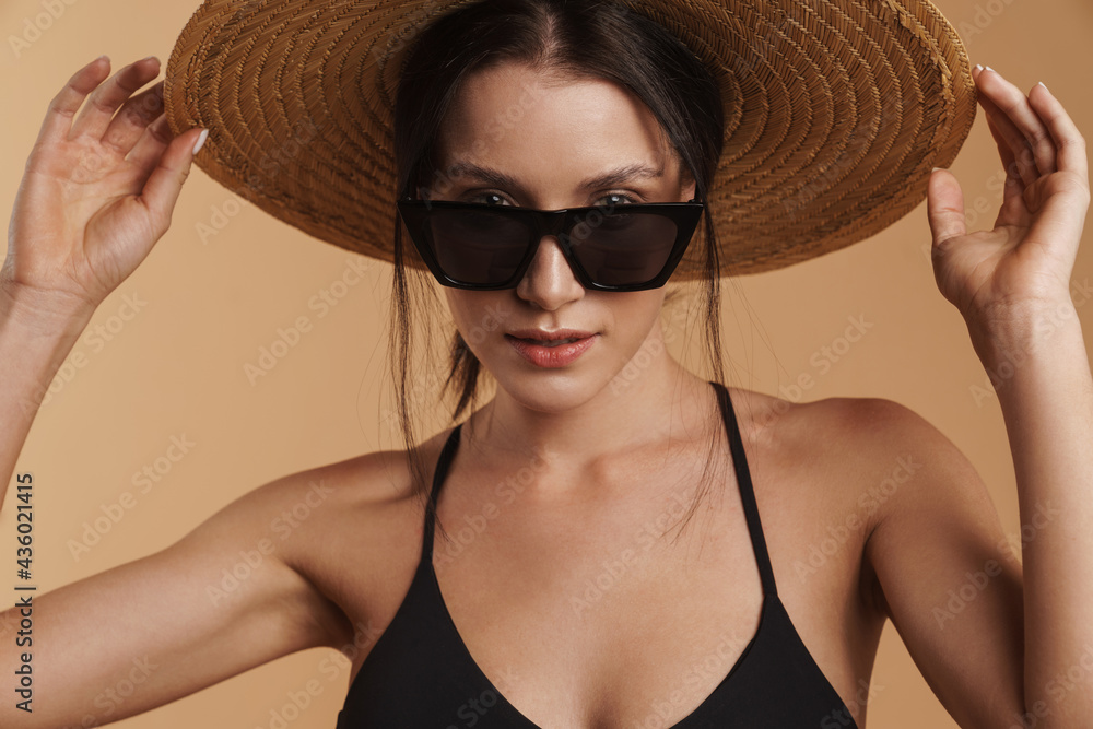 Young brunette woman in straw hat posing and looking at camera Young brunette woman in straw hat posing and looking at camera