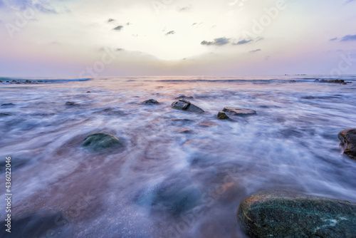 Beach water slow shutter speed and sunrise with rocks 