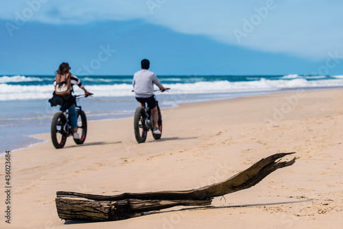 couple riding bicycle or fat bike on sunny beach photo
