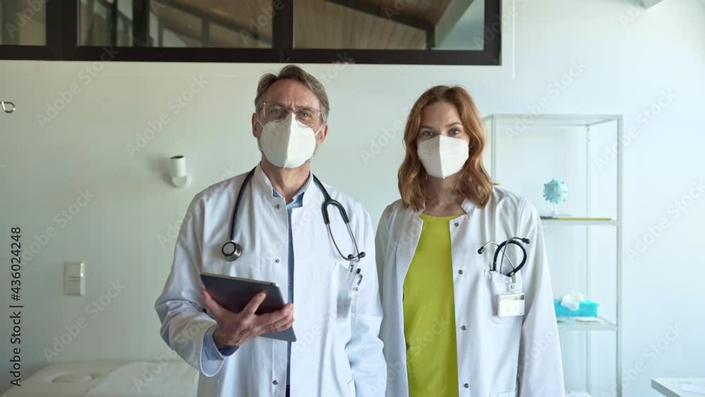 Confident doctors with protective face masks standing in practice Confident doctors with protective face masks standing in practice