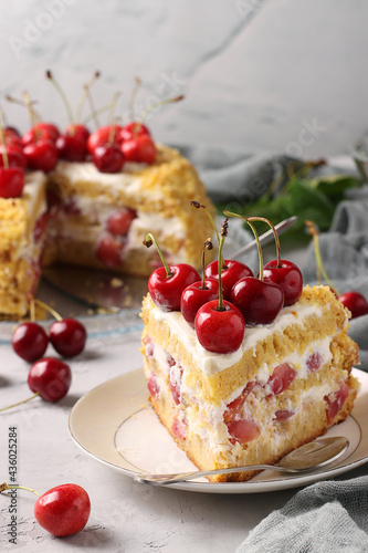 Piece of homemade cake with sweet cherries is located on a plate on a gray background. Vertical format