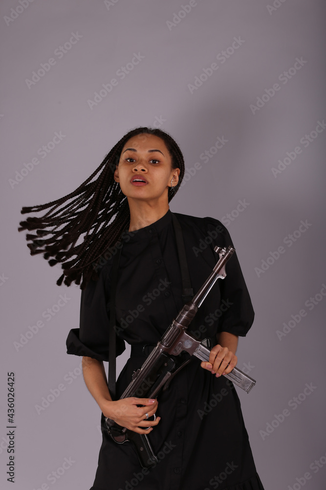 Beautiful woman in black dress with vintage submachine gun