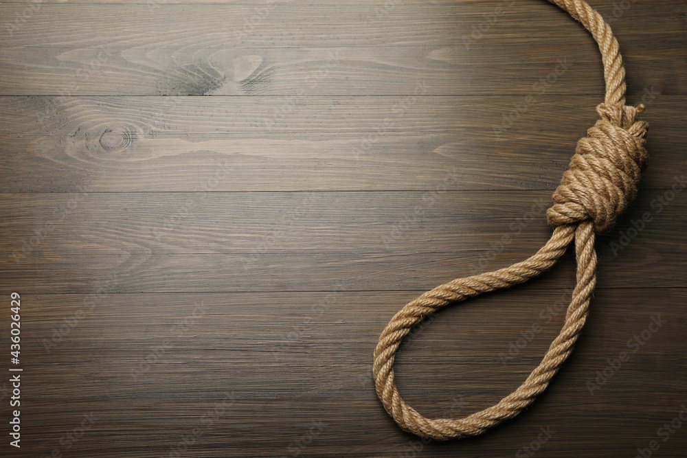 Rope noose on wooden table, top view. Space for text