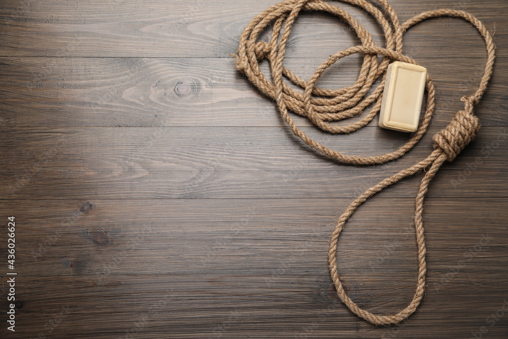 Rope noose and soap bar on wooden table, flat lay. Space for text
