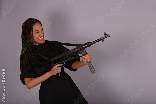 Beautiful woman in black dress with vintage submachine gun