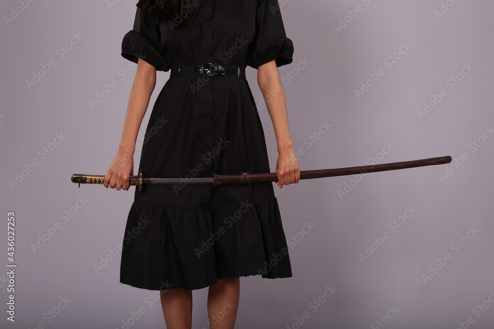 Woman in black dress with katana sword in scabbard Woman in black dress with katana sword in scabbard