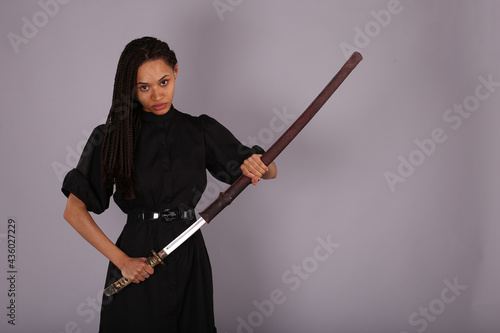 Woman in black dress with katana sword in scabbard