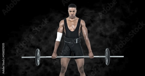 Composition of african american male weightlifter with barbell with smoke on black background