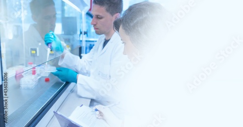 Composition of male and female lab technicians at work, with white blurred copy space to right
