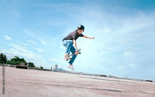 Teenager skateboarder does an ollie trick on background of blue sky gradient