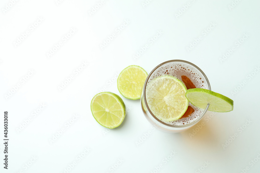 Glass of beer with lime on white background
