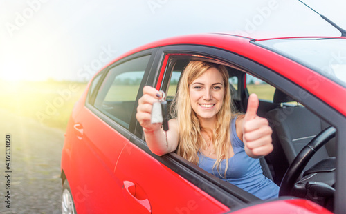 A beautiful woman in a car holds a car key in her hands. Happy young woman in the car.