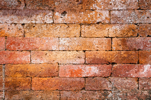 Solid weathered brick wall with orange bricks.