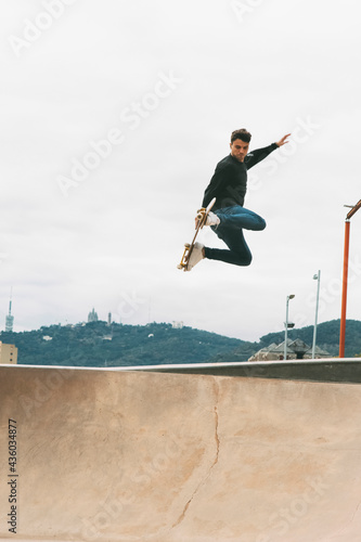 skater jumping high in the air with a snake board in a skate park