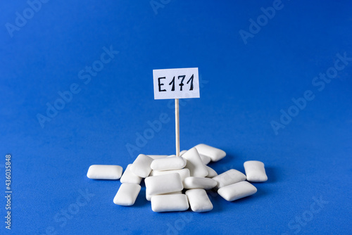 Heap of chewing gum with e171 dangerous additive sign on blue background photo