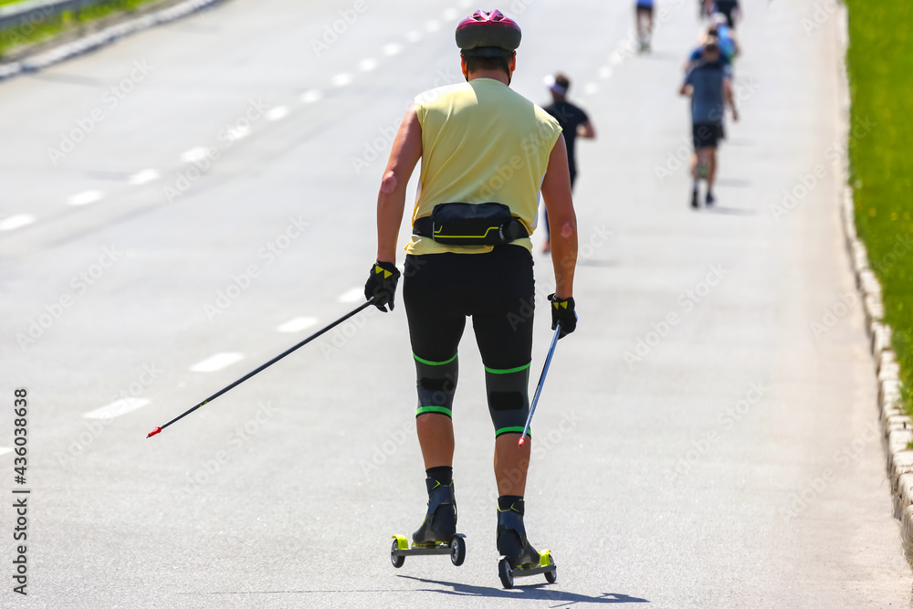 Fototapeta premium athlete rides roller-skis on the asphalt on the road