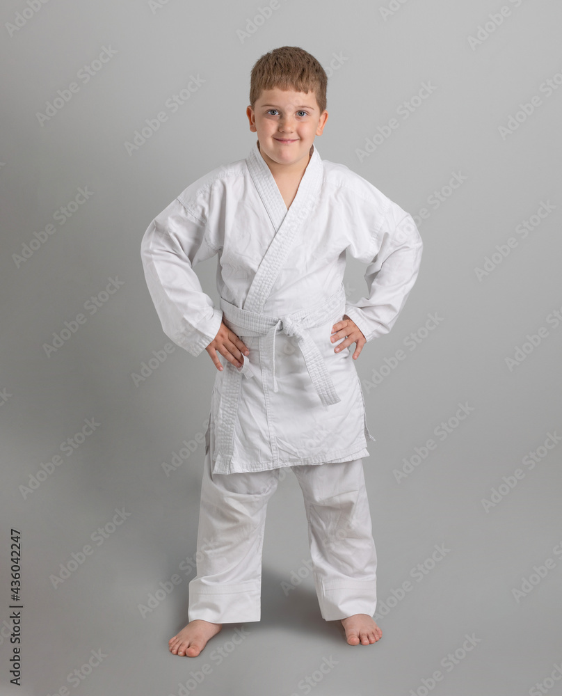 Boy in white kimono smiles on gray background Boy in white kimono smiles on gray background