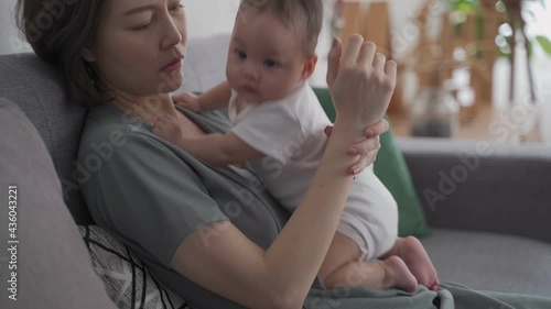 asian woman mother holding heavy baby infant get hurt in wrist and massaging to relieve pain. mother suffering from holding baby. tendon joint injury. photo