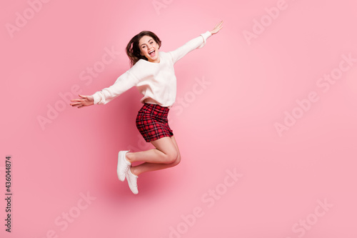 Full body profile side photo of young excited girl happy positive smile jump up hands wings fly isolated over pink color background
