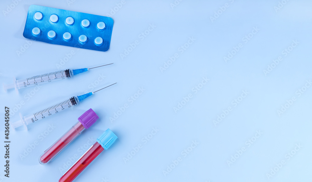 test tubes with blood tests, tablets and syringes with medicines on a blue background. the concept of treatment based on the results of the analysis test tubes with blood tests, tablets and syringes with medicines on a blue background. the concept of treatment based on the results of the analysis