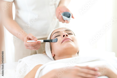 Young beautiful woman healthy spa treatment. Beautician doing facial mask.