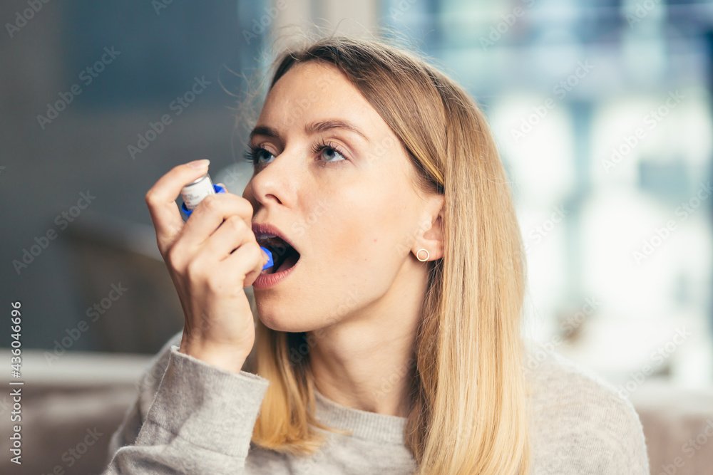 Young woman using inhaler while suffering from asthma at home Young woman using inhaler while suffering from asthma at home