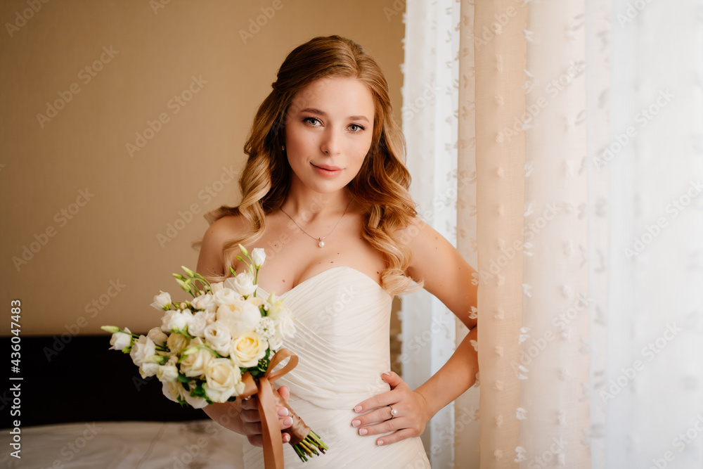 portrait of a beautiful bride with a bouquet by the window. Wedding traditions.