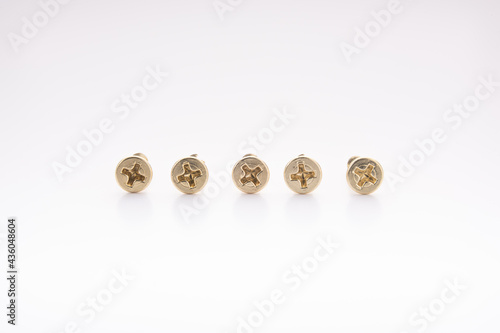 Five brass screws on a white surface gradient