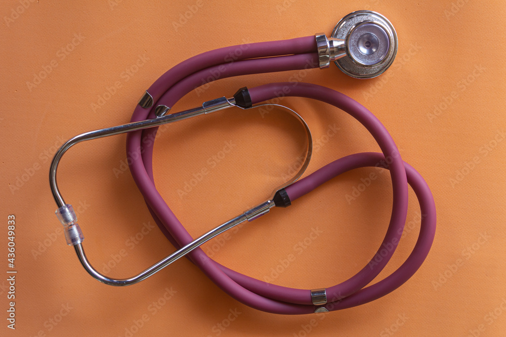 Red stethoscope, equipment to examine respiration and heartbeat. Orange background. Red stethoscope, equipment to examine respiration and heartbeat. Orange background.