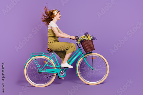 Fototapeta Naklejka Na Ścianę i Meble -  Profile side view portrait of pretty cheerful girl driving cycle fast speed wind blowing hair isolated over violet purple color background