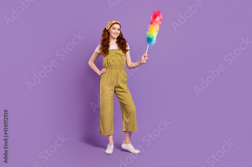 Full length body size view of pretty cheerful girl wiping dust fluffy stick isolated over violet purple color background © deagreez