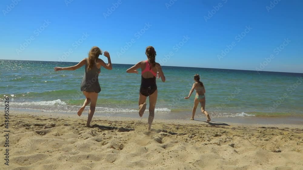 Happy girls having fun on a beach running and jumping to the sea enjoying summer holidays slow motion Happy girls having fun on a beach running and jumping to the sea enjoying summer holidays slow motion