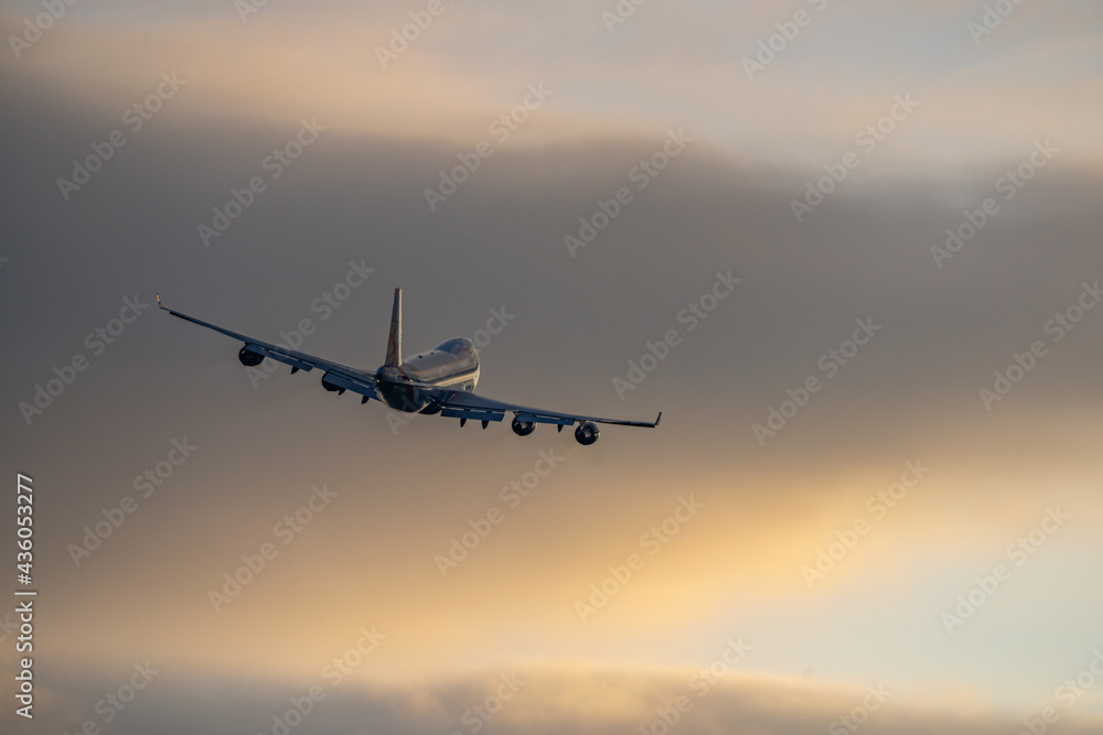 Jumbo jet four big engines flying off taking tourists abroad from airport on holiday into golden sunset summer sky. Creamy gold clouds and silhouette of aeroplane taking off and flying away. Jumbo jet four big engines flying off taking tourists abroad from airport on holiday into golden sunset summer sky. Creamy gold clouds and silhouette of aeroplane taking off and flying away.